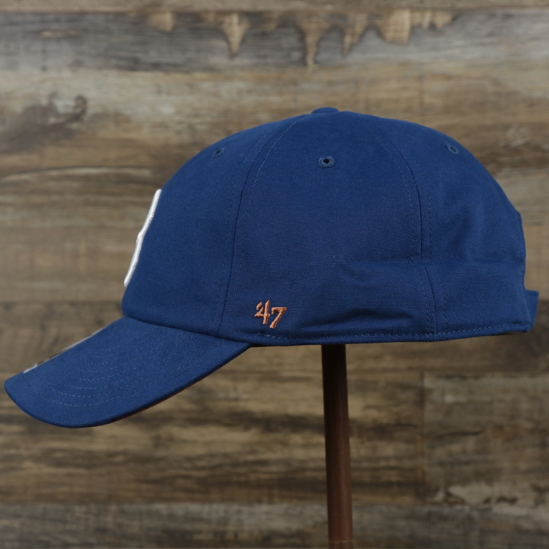 The wearer's left on the Cooperstown Brooklyn Dodgers Cooperstown Collection Side Patch Leather Brown Undervisor Dad Hat | Vintage Royal Blue Dad Hat