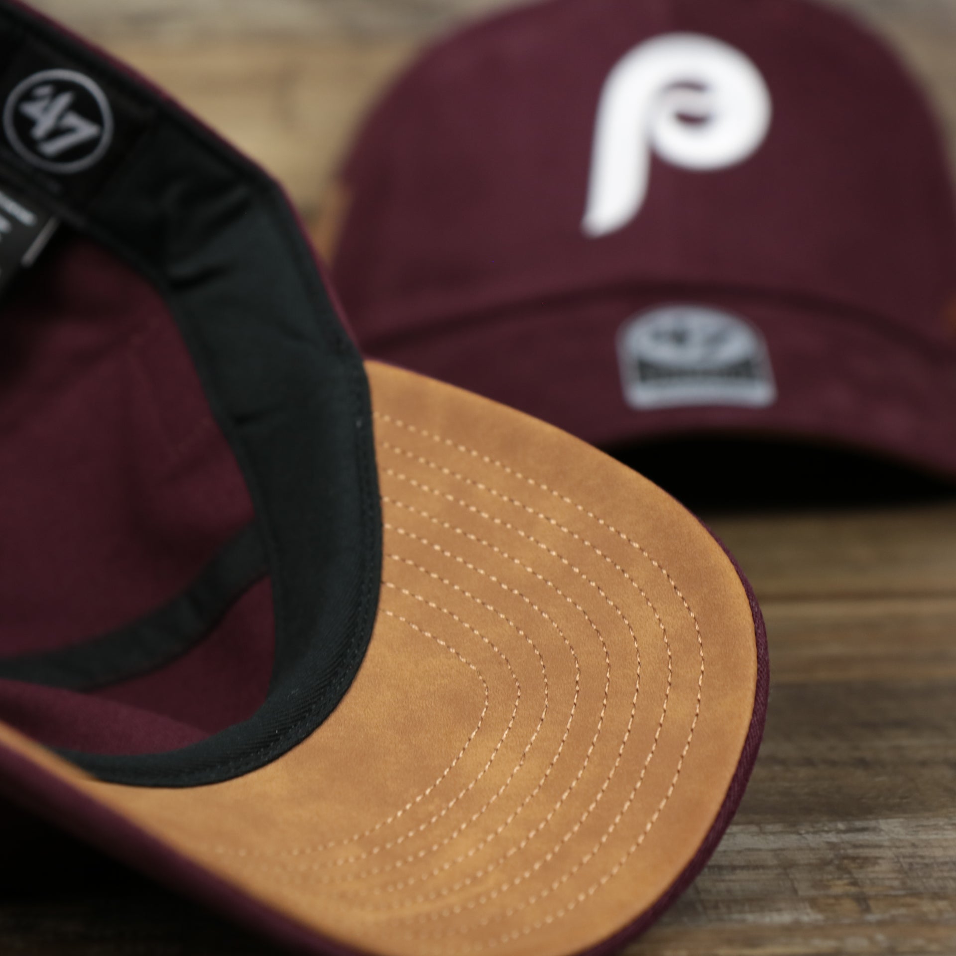 The Leather Undervisor on the Cooperstown Philadelphia Phillies Cooperstown Collection Side Patch Leather Brown Undervisor Dad Hat | Maroon Dad Hat