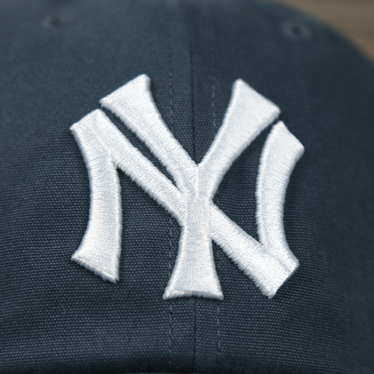 The Yankees Logo on the Cooperstown New York Yankees Cooperstown Collection Side Patch Leather Brown Undervisor Dad Hat | Vintage Navy Dad Hat