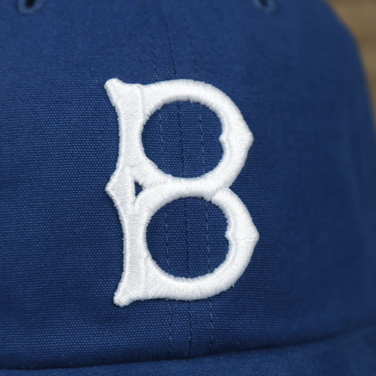 The Brooklyn Dodgers Logo on the Cooperstown Brooklyn Dodgers Cooperstown Collection Side Patch Leather Brown Undervisor Dad Hat | Vintage Royal Blue Dad Hat