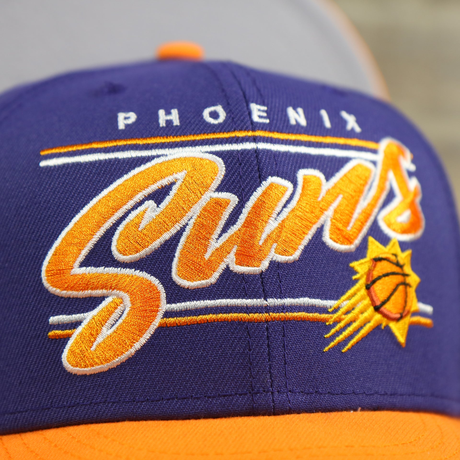 suns logo on the Phoenix Suns Team Script College Bar 9Fifty Snapback Hat | Purple/Orange Suns 950 Snap Cap