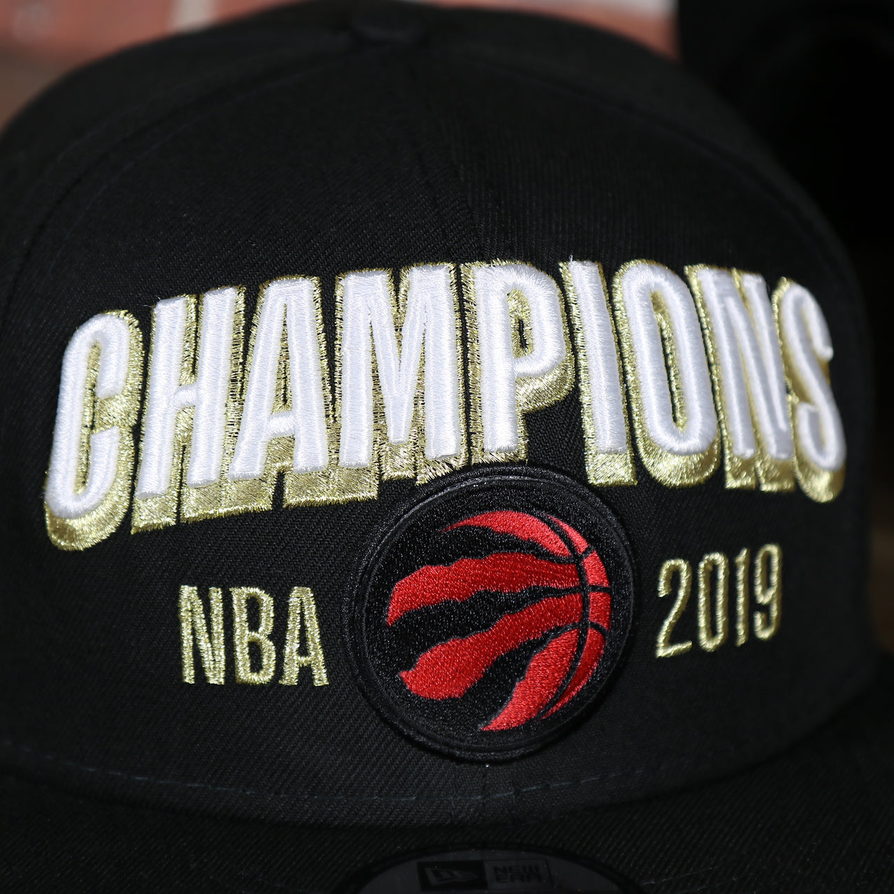raptors logo on the Men's Toronto Raptors New Era Black 2019 NBA Finals On Court Champions Locker Room 9FIFTY Snapback Hat