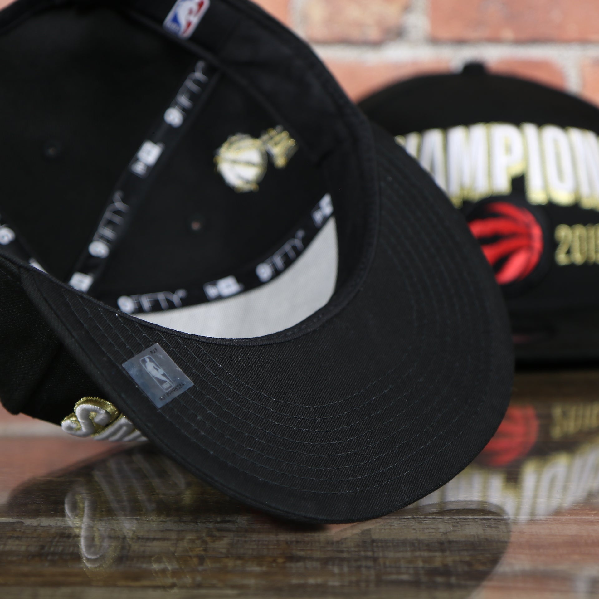 black under visor on the Men's Toronto Raptors New Era Black 2019 NBA Finals On Court Champions Locker Room 9FIFTY Snapback Hat