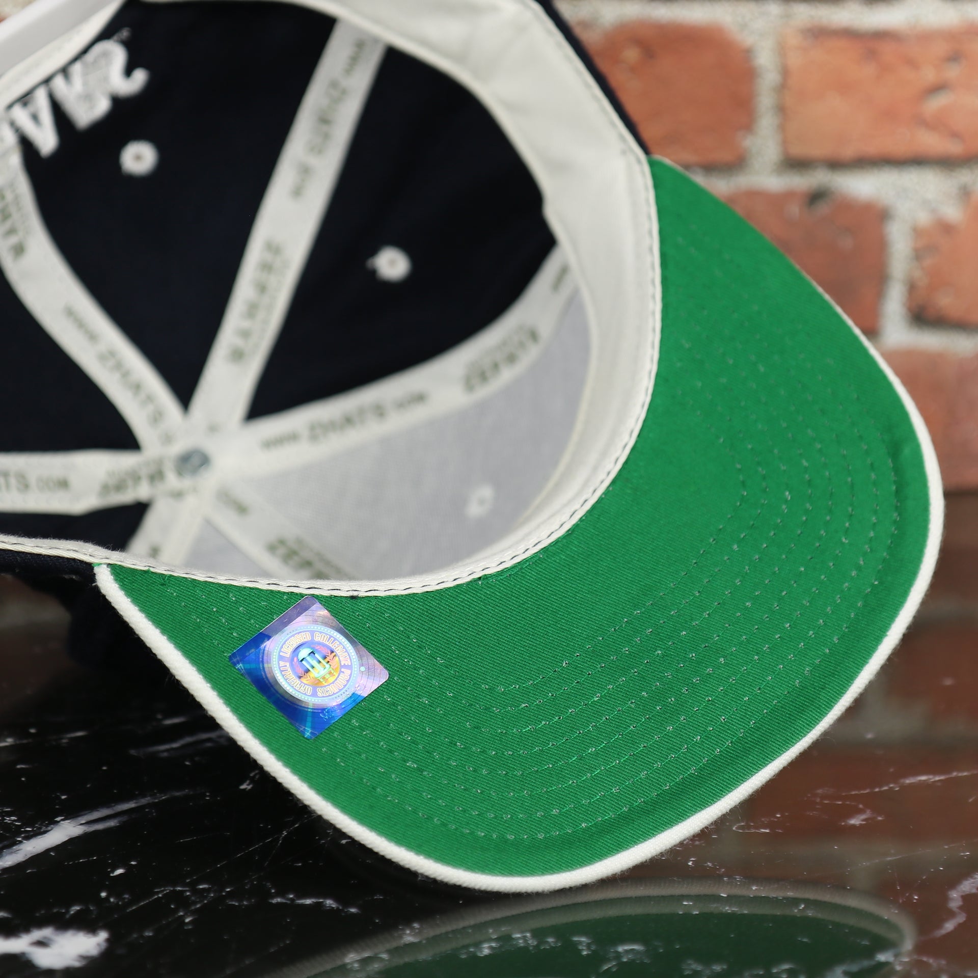 green under visor on the BYU Cougars Green Bottom Arched Wordmark Snapback Cap | Navy Blue Snap Cap