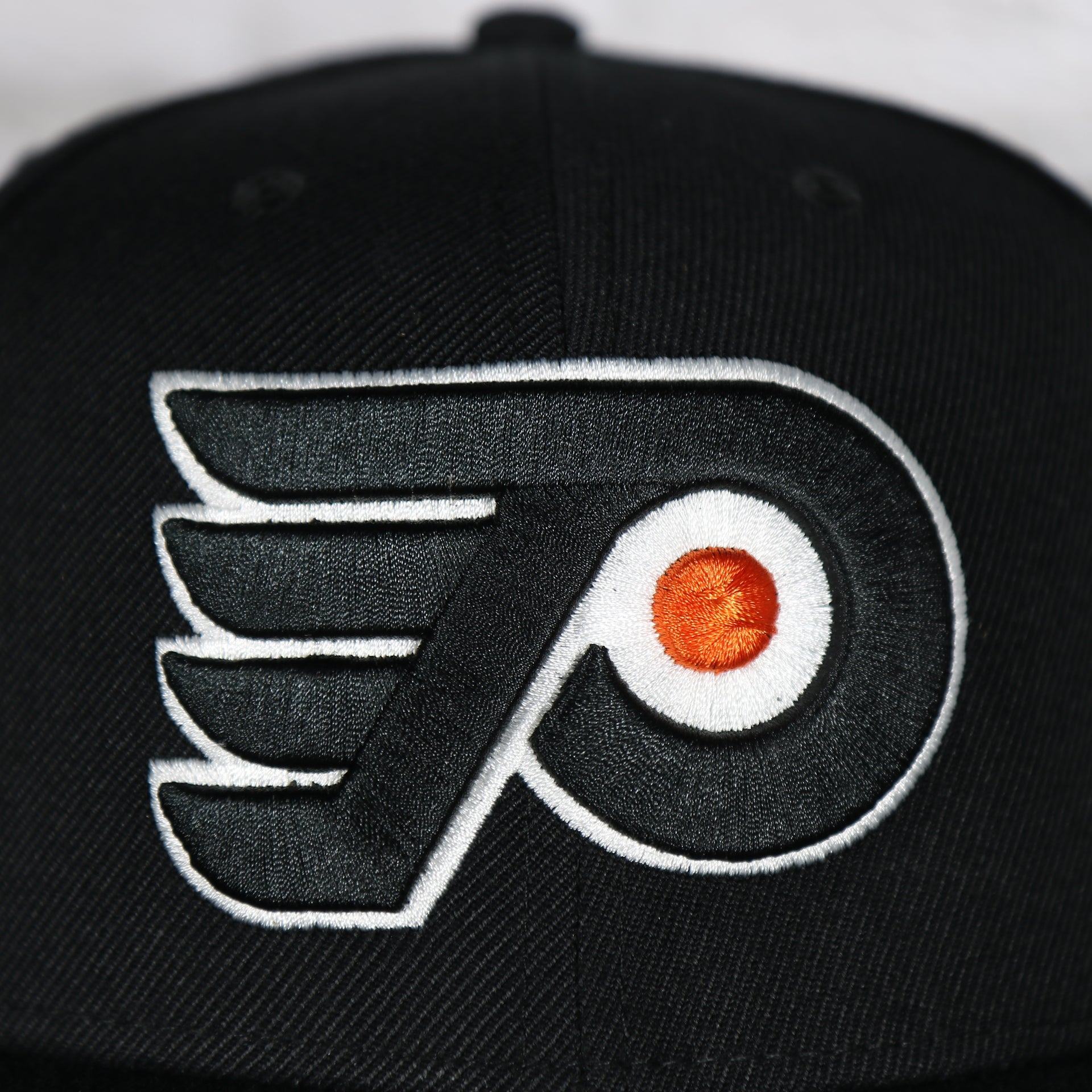 Close up of the front logo on the Philadelphia Flyers No Shot Grey Undervisor Black Snapback Hat