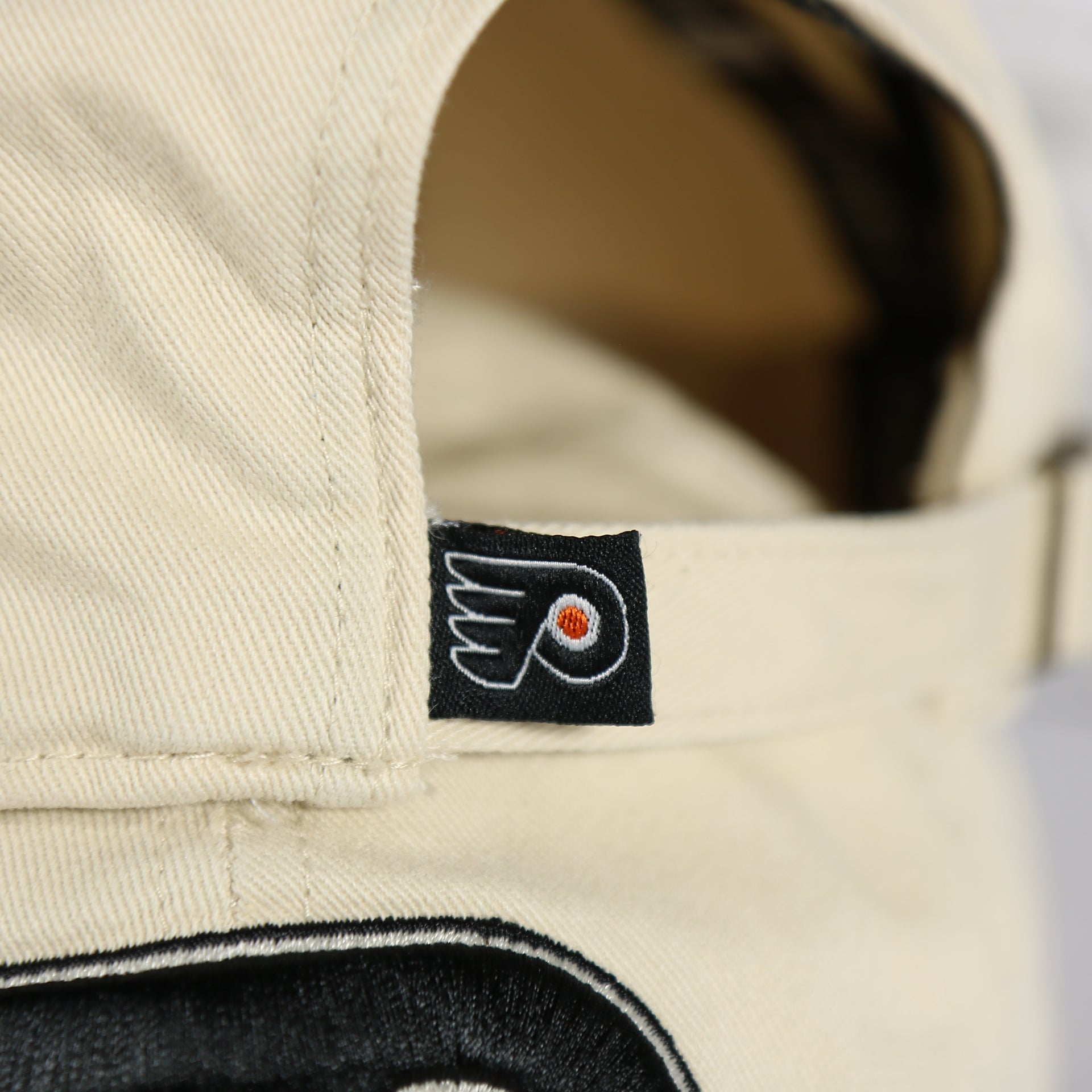 Close up of the Flyers label on the back of the Philadelphia Flyers Natural Unstructured Crown Black Curved Brim Adjustable Dad Hat