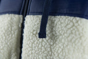 The adjustable draw strings for the hood on the nylon sherpa cream zip up hoodie are navy blue and feature a square end