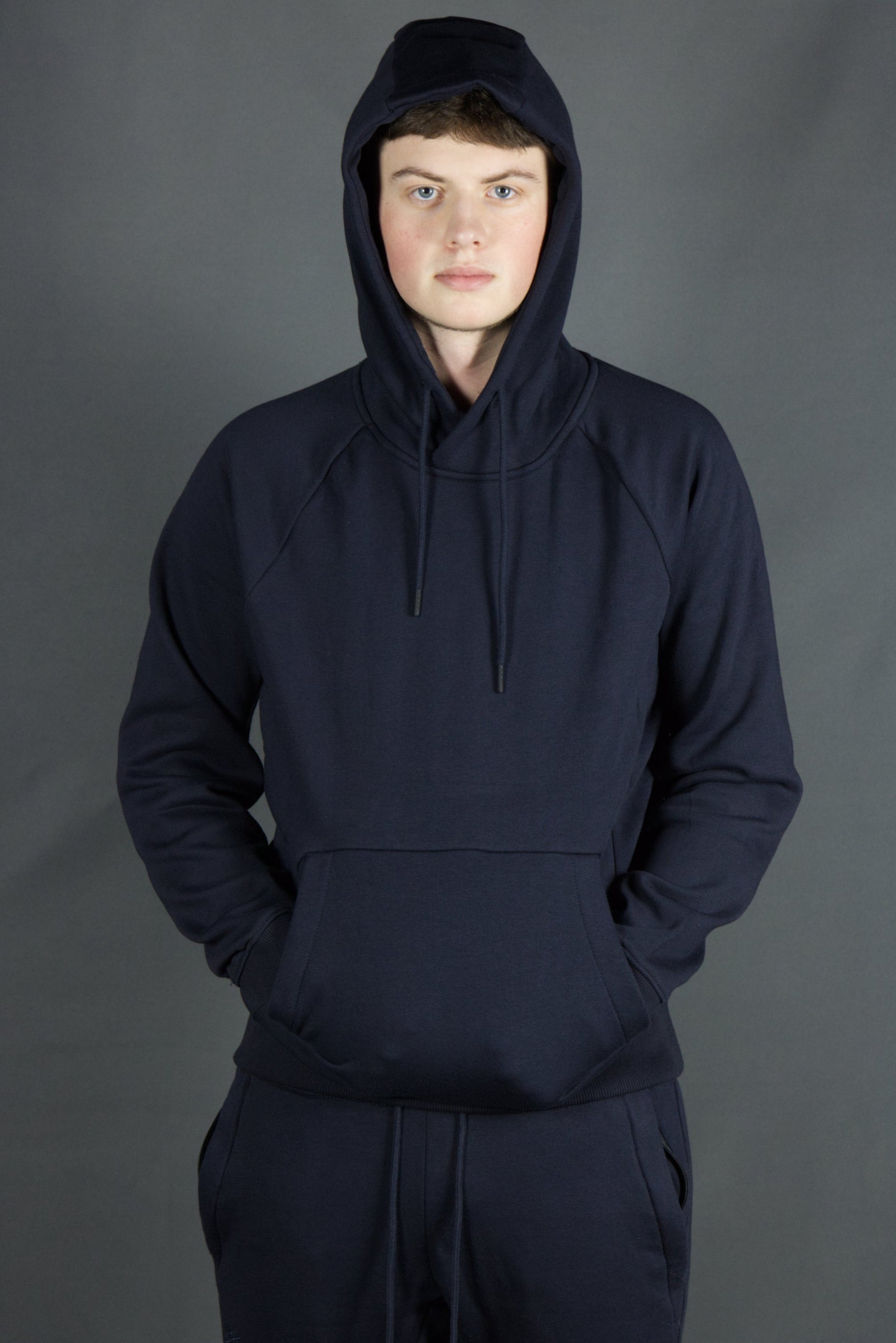 A model wearing the navy blue basic fleece pullover hoodie by Jordan Craig.