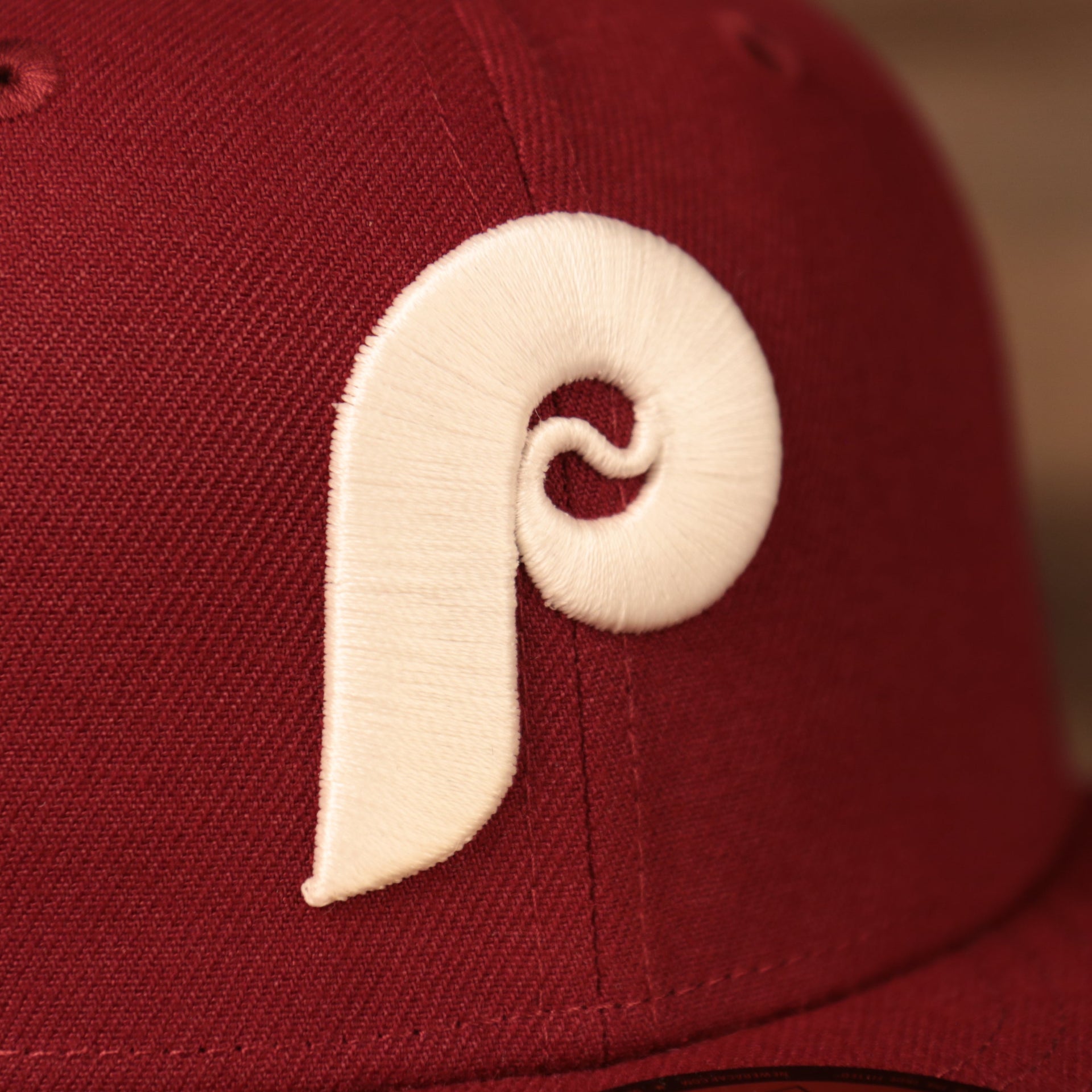 A close up of the white retro Phillies logo on the front side of the glow in the dark white flower underbrim Philadelphia Phillies side patch fitted 59fifty hat by New Era.