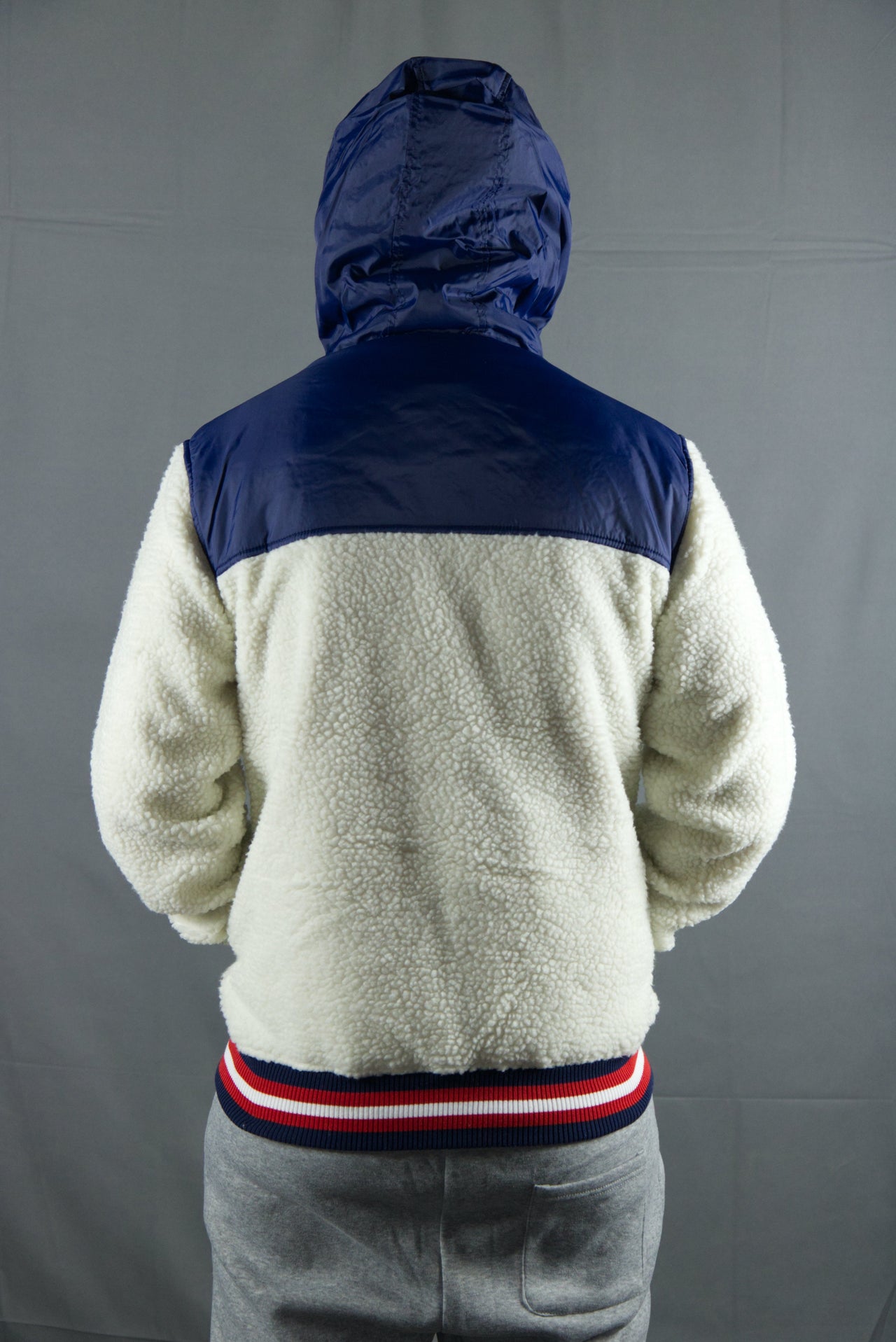 The hood and upper back of the cream zipper sherpa hoodie are made out of a navy blue nylon material