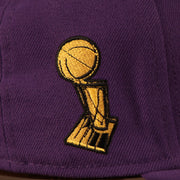 A close shot of the Larry Obrien Trophy patch on the wearer's right side of the purple Los Angeles Lakers all over embroidered 5950 fitted cap by New Era.
