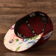 The white floral bottom brim of the maroon retro Phillies side patch fitted 59fifty cap by New Era.