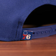 The backside of the youth New Era Philadelphia 76ers royal blue 9fifty snapback hat has an adjustable strap.