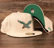 The cream Philadelphia Eagles retro kelly logo 59fifty fitted hat with green underbrim.