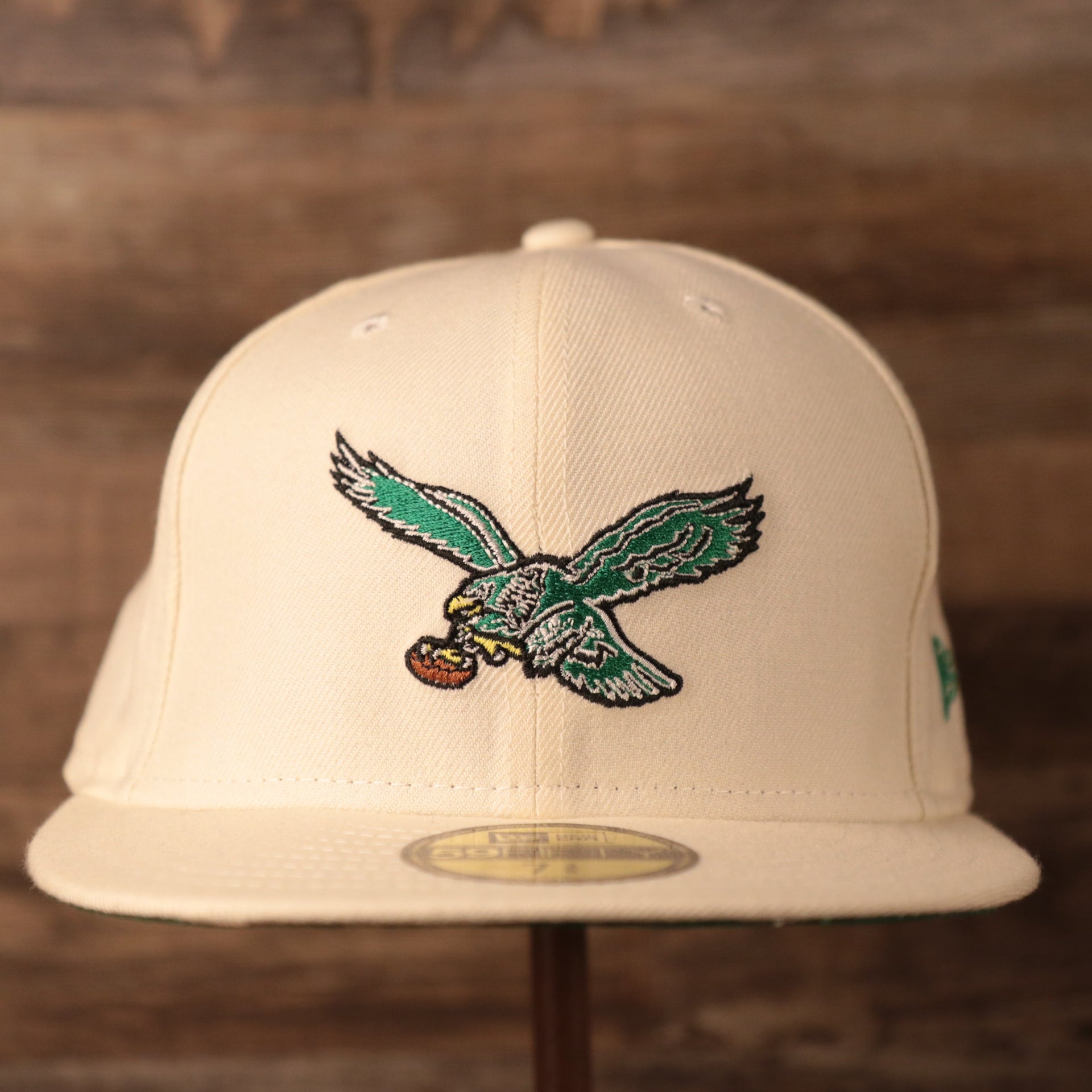 The retro green kelly logo patch on the front side of the Philadelphia Eagles cream 5950 fitted hat by New Era.