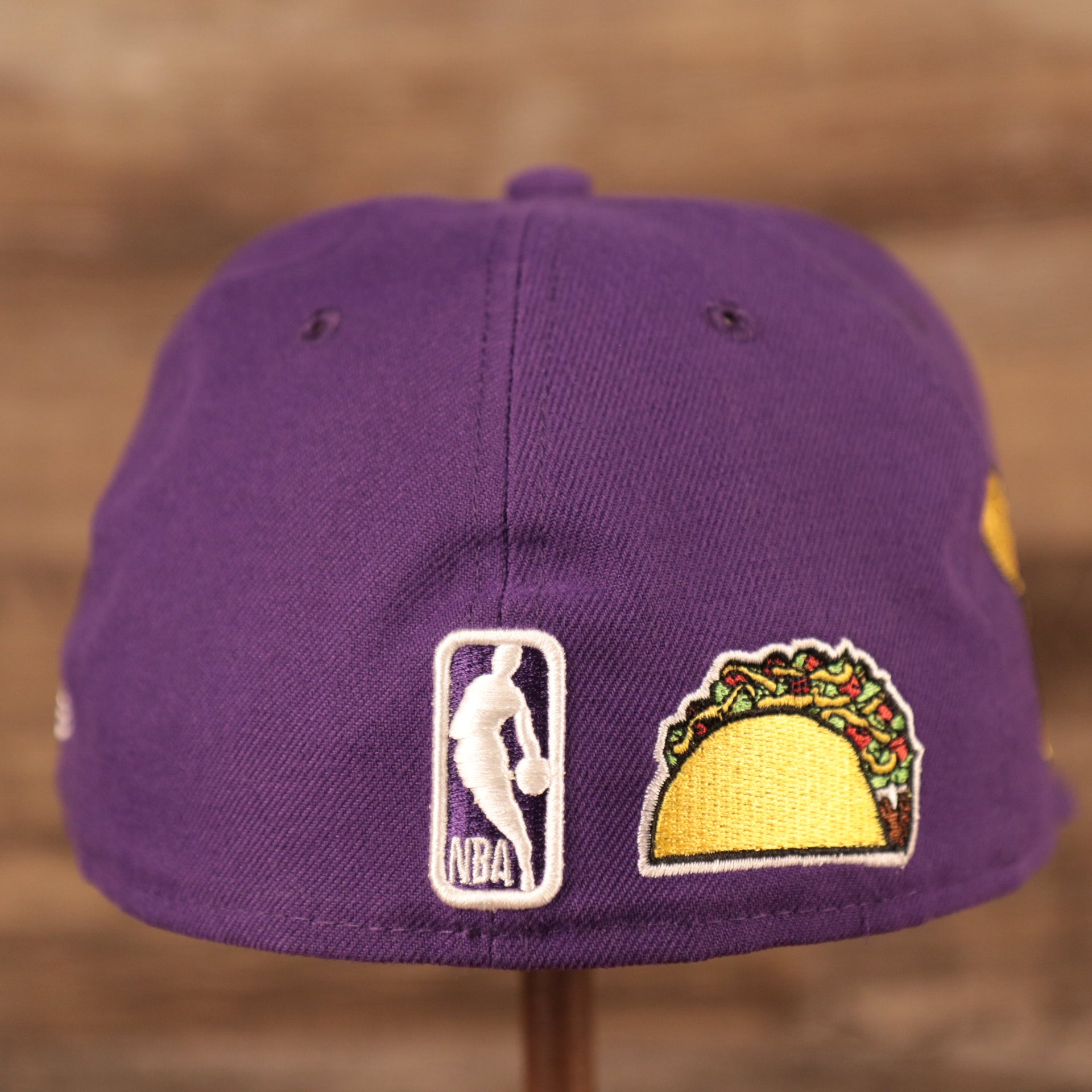 The NBA logo and the taco patch on the backside of the purple Los Angeles Lakers all over embroidery fitted cap by New Era.