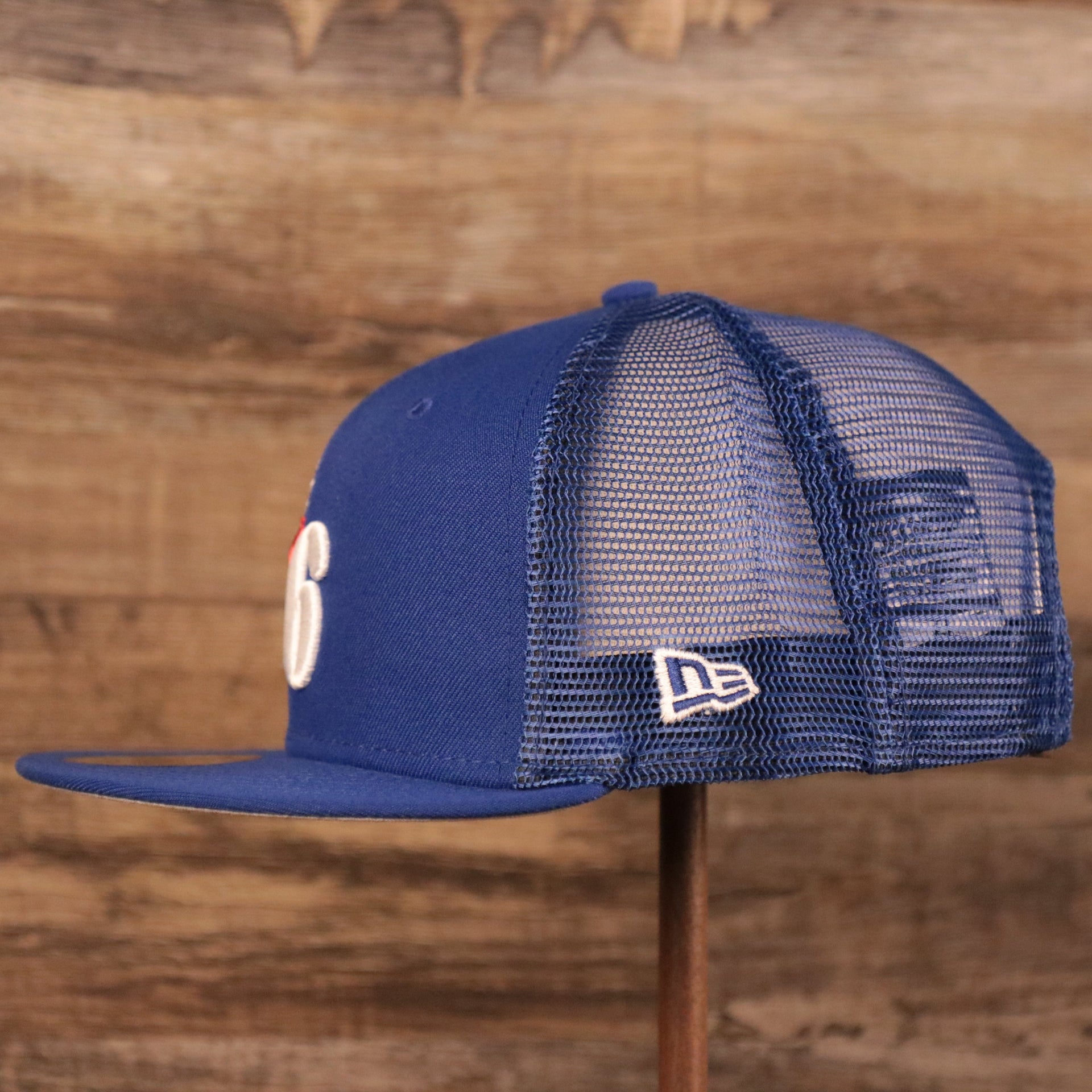 The left side of the Philadelphia 76ers royal blue trucker hat has the logo of New Era.