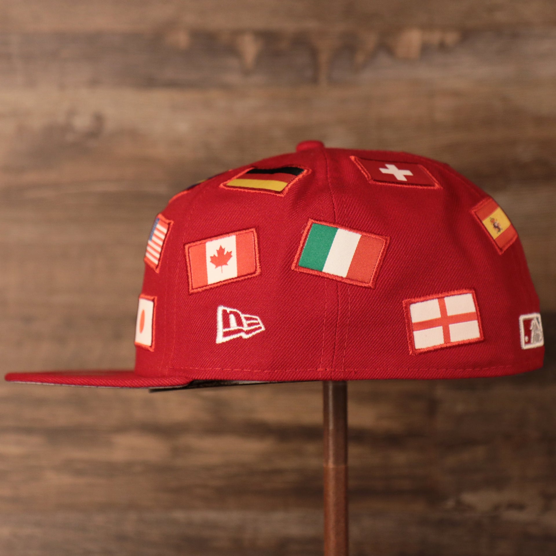 the wearers left side has the flags from the countries of Canada, Germany, and Italy Phillies World Flags Gray Bottom Fitted Cap | Philadelphia Phillies International Flags Red Grey Under Brim Fitted Cap