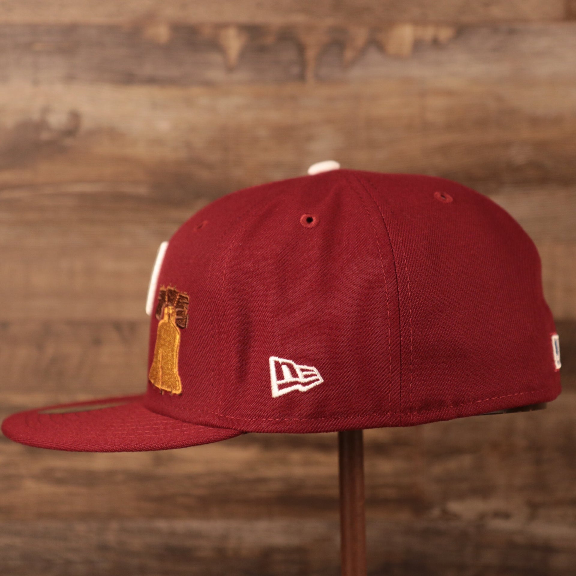 The wearer's left side of the maroon Philadelphia Phillies 1980 World Series 5950 all over patch fitted cap has the logo of New Era in white.