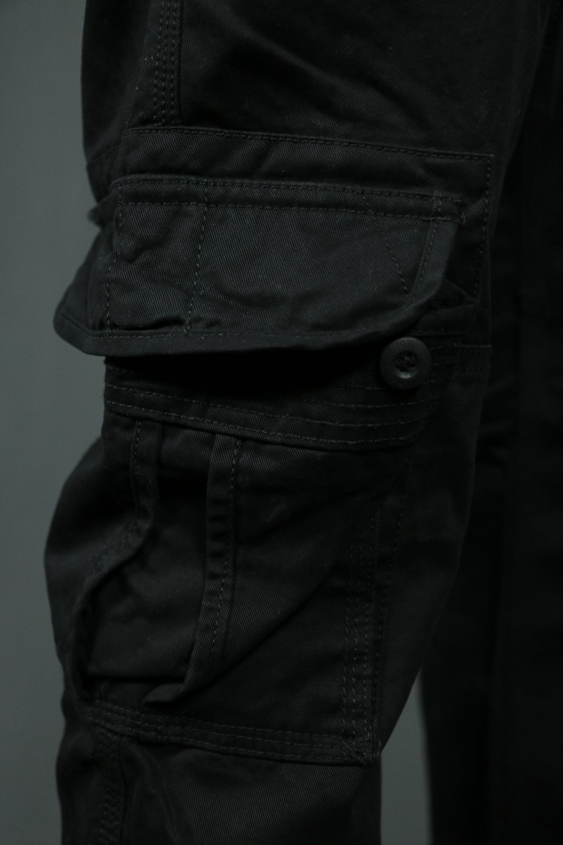 One of the two buttoned pockets of the black Jordan Craig cargo pants for men.