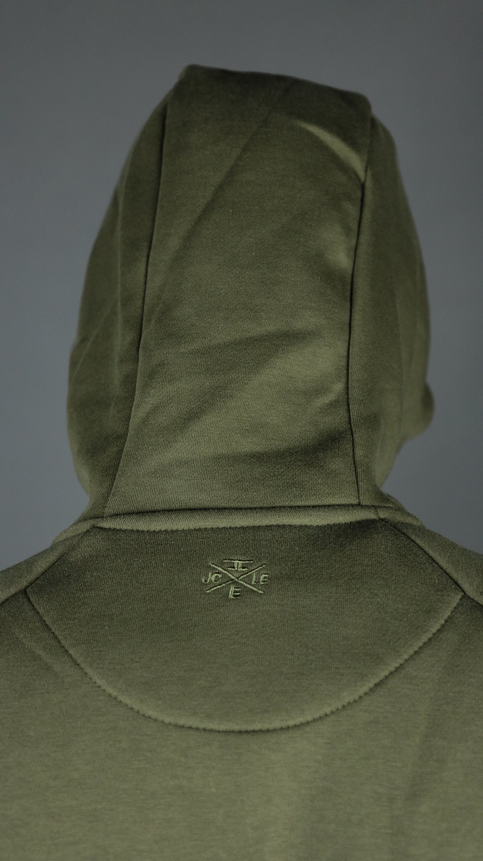 The back of the hood of the military olive green hoodie by Jordan Craig.