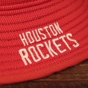 A closeup of the white Houston Rockets patch on the red Houston Rockets bucket hat by New Era.