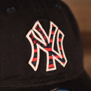 A closeup shot of the Yankees logo on the front side of the navy fourth of July 2021 920 dad hat.