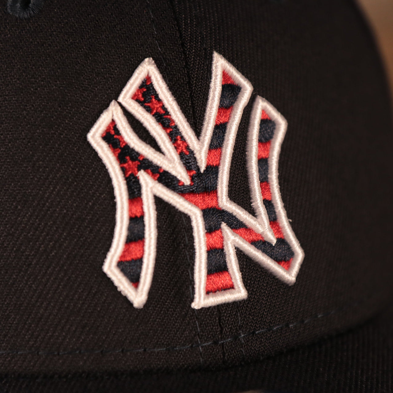 A closeup shot of the Yankees logo on the front side of the New York Yankees 2021 fourth of July navy 39thirty flexfit hat.