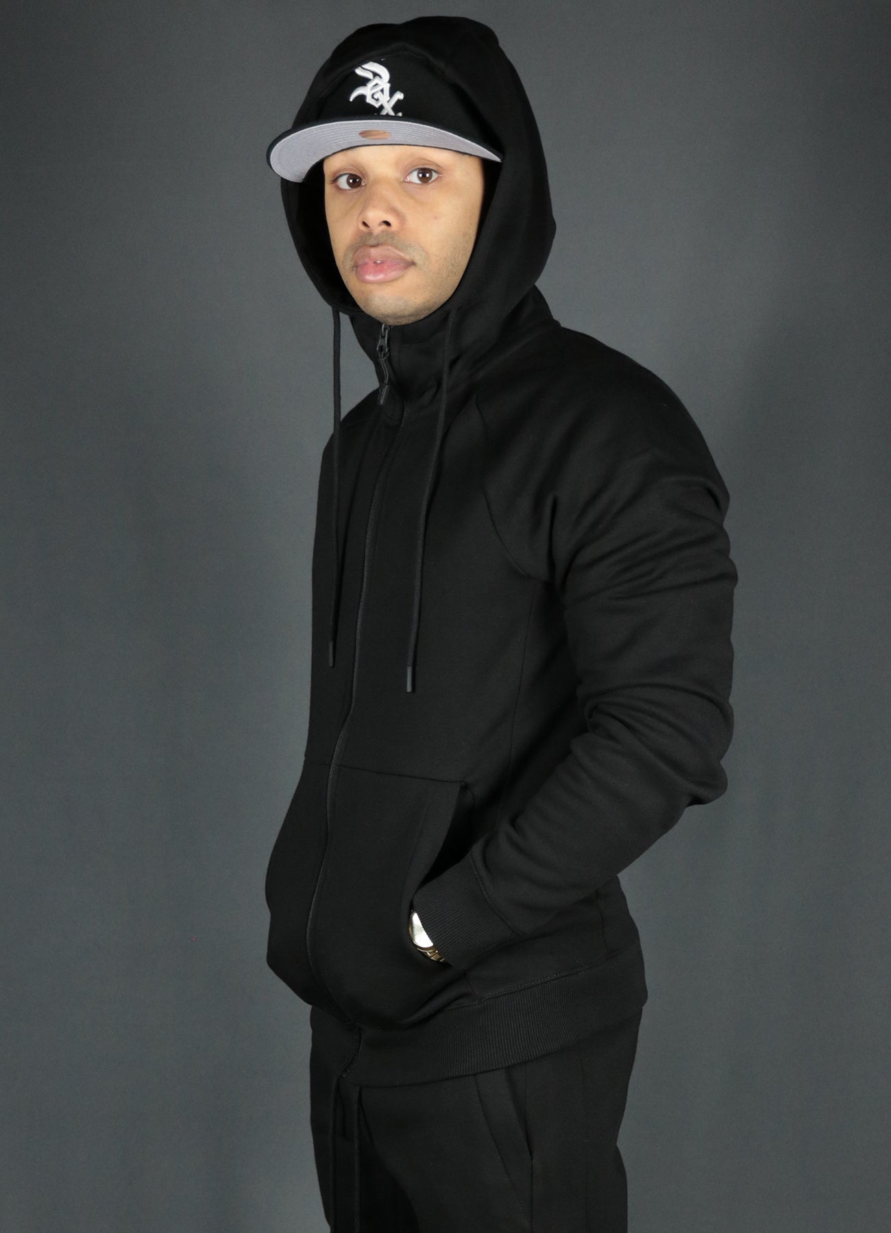 A model wearing the black zipup hoodie by Jordan Craig with the black Jordan Craig joggers.