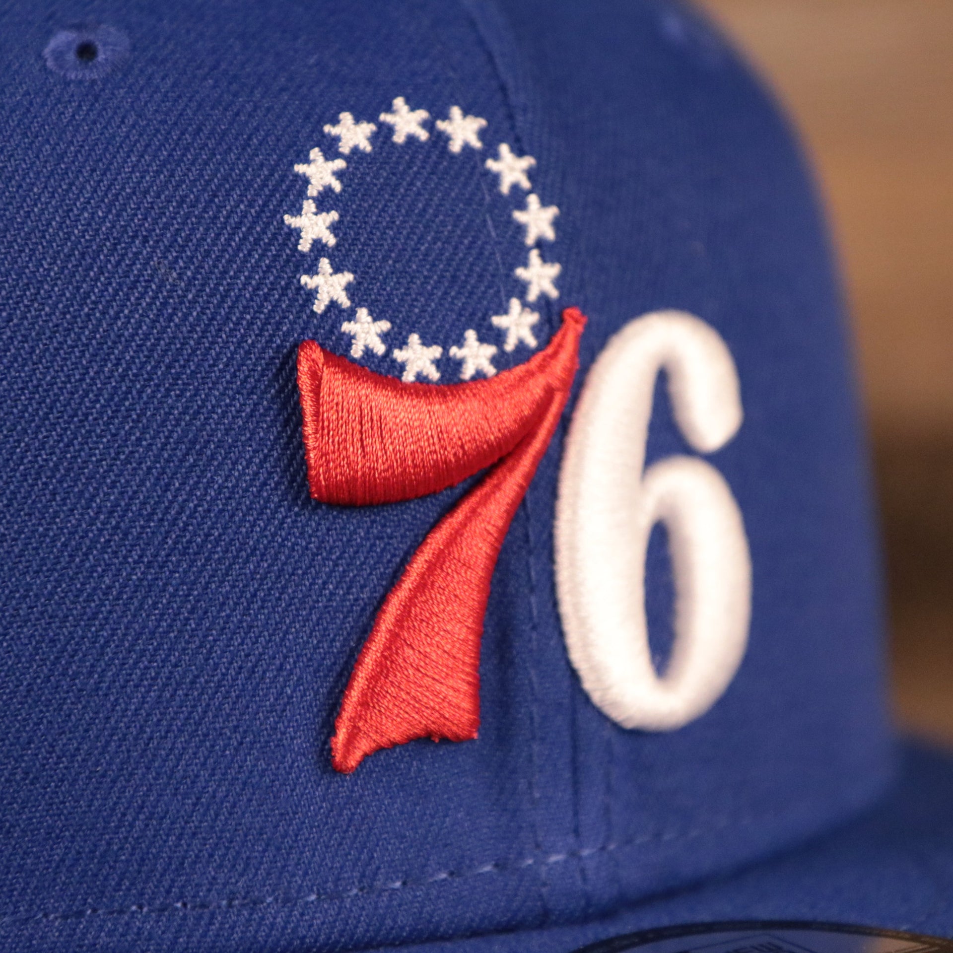 The Philadelphia 76ers logo on the front side of the royal blue New Era 920 snapback hat.