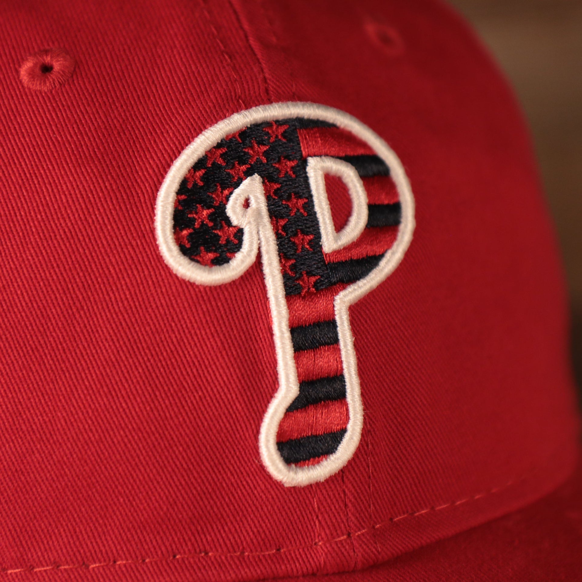 A closeup shot of the Phillies logo on the front side of the Philadelphia Phillies red fourth of July 2021 920 dad hat.