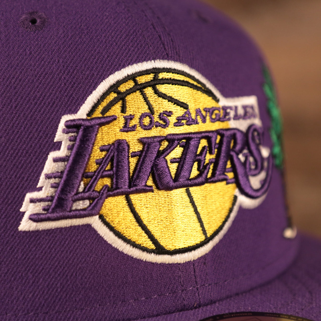 A close up of the Los Angeles Lakers logo on the front side of the purple Los Angeles Lakers 5950 all over embroidery fitted cap by New Era.