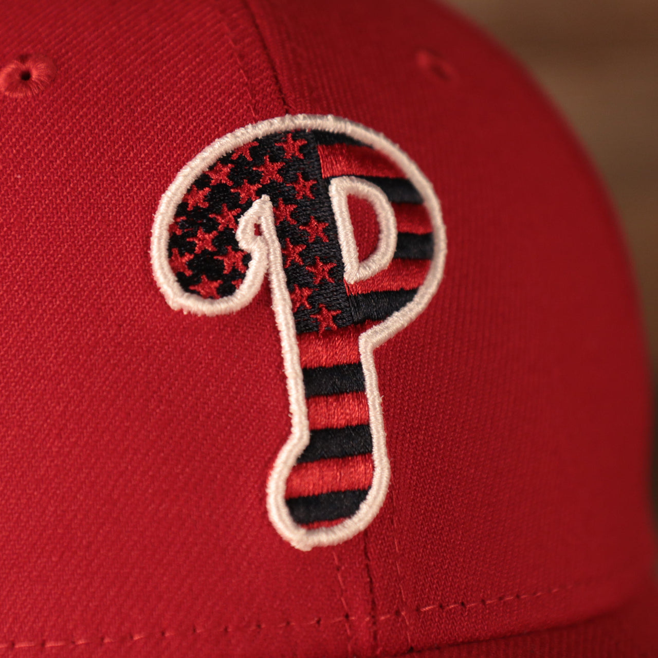 A closeup shot of the Phillies logo on the front side of the Philadelphia Phillies red fourth of July 2021 3930 flexfit hat.