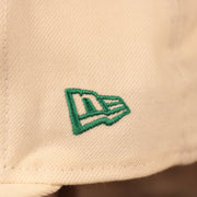 A close up shot of the green New Era logo embroidered on the left side of the cream Philadelphia Eagles gray bottom brim retro 5950 fitted hat.