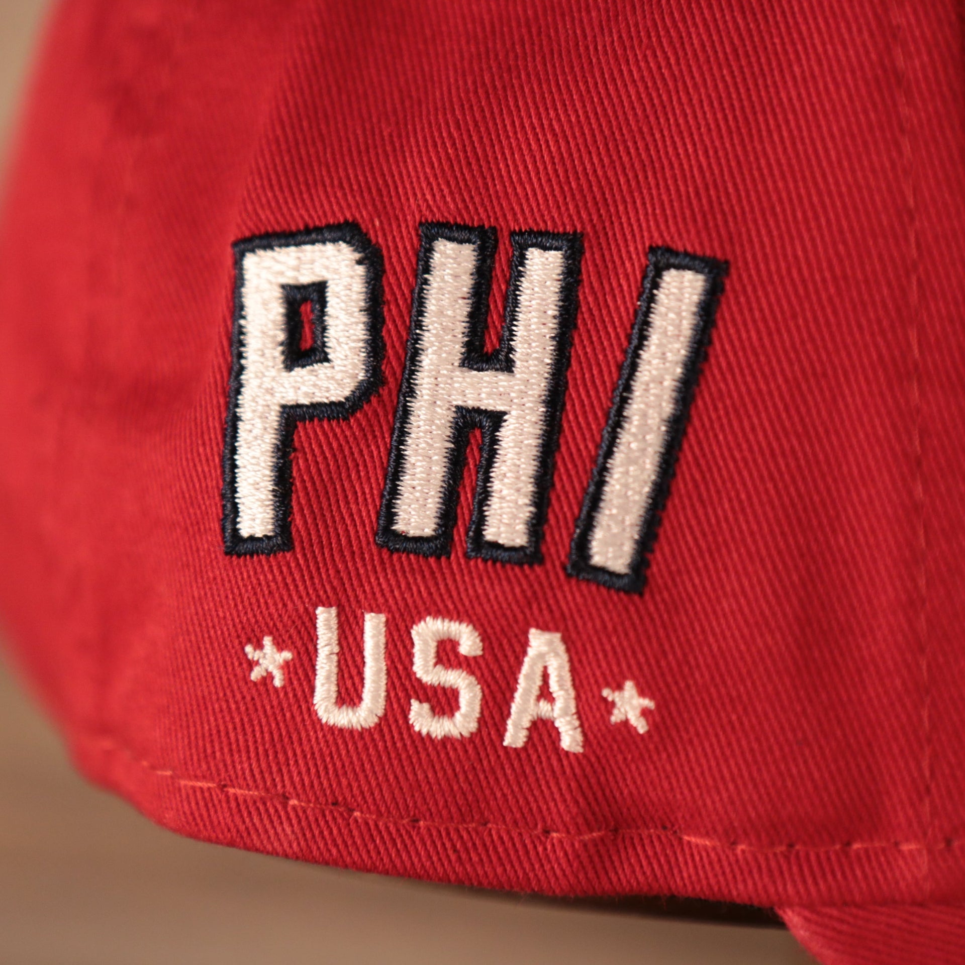 A closeup shot of the PHI USA patch on the wearer's right side of the red MLB fourth of July 2021 Philadelphia Phillies 920 dad hat.