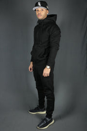 A model wearing the Jordan Craig black joggers and black zipup hoodie.