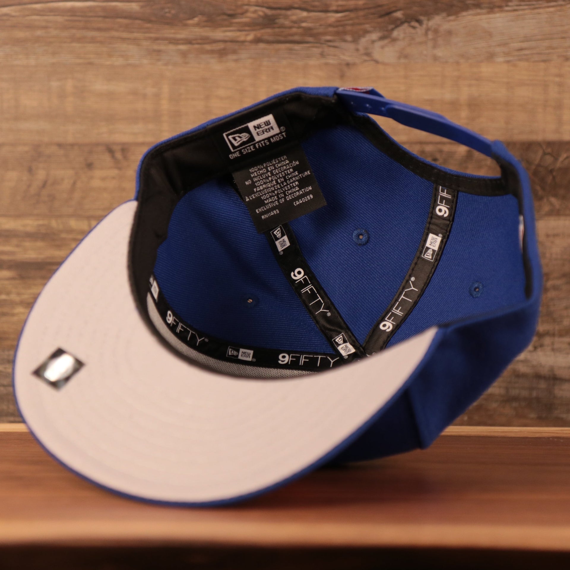An inside view of the youth grey bottom Philadelphia 76ers royal blue logo tear 9fifty snapback hat.