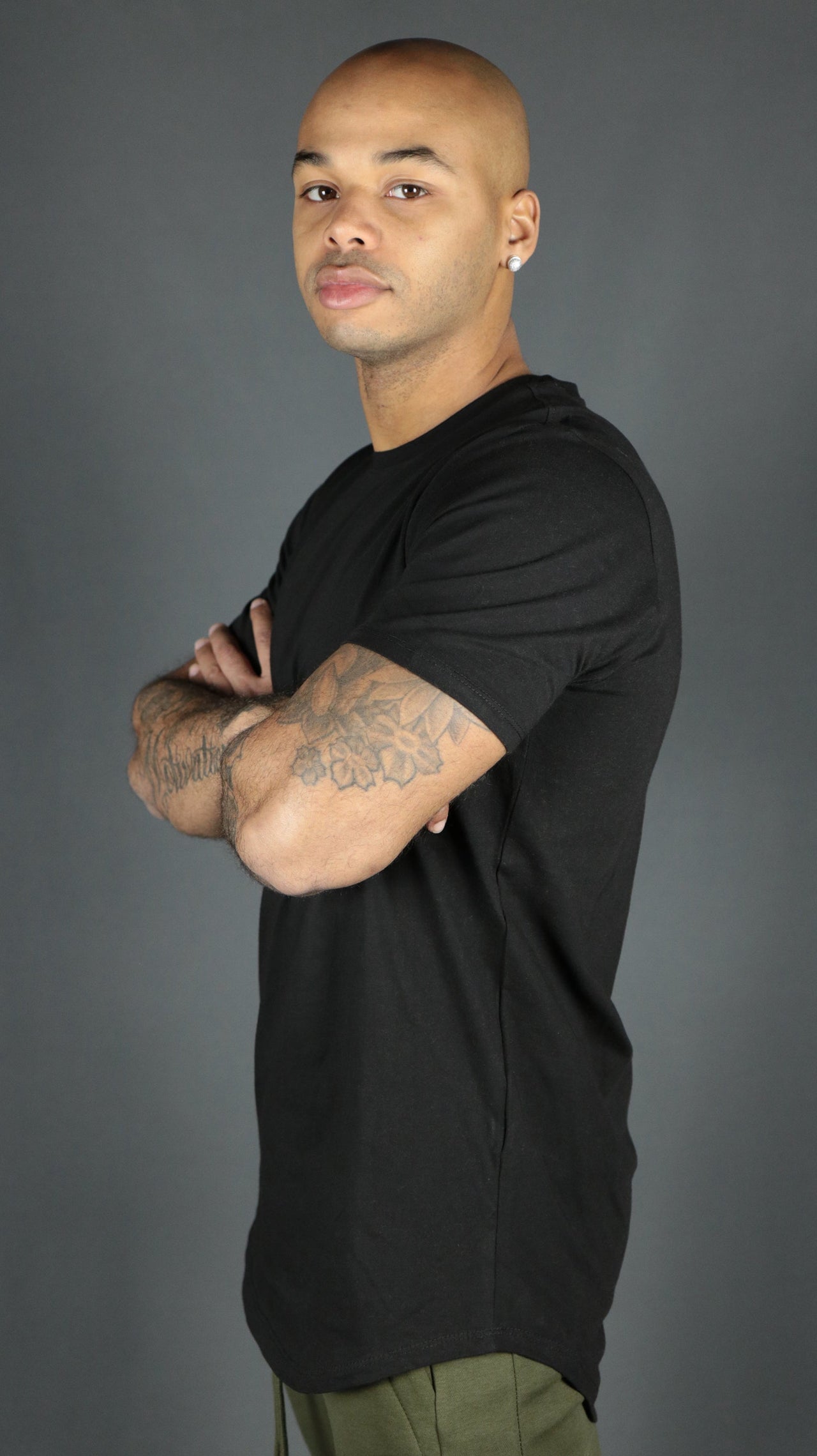 A model wearing a black men's curved hem scoop bottom tshirt by Jordan Craig.