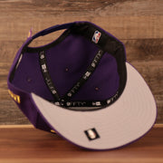 The gray bottom brim of the Los Angeles Lakers purple logo tear 9fifty snapback hat.