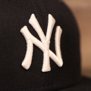 The New York Yankees logo patch on the front side of the navy New Era mesh snapback hat.
