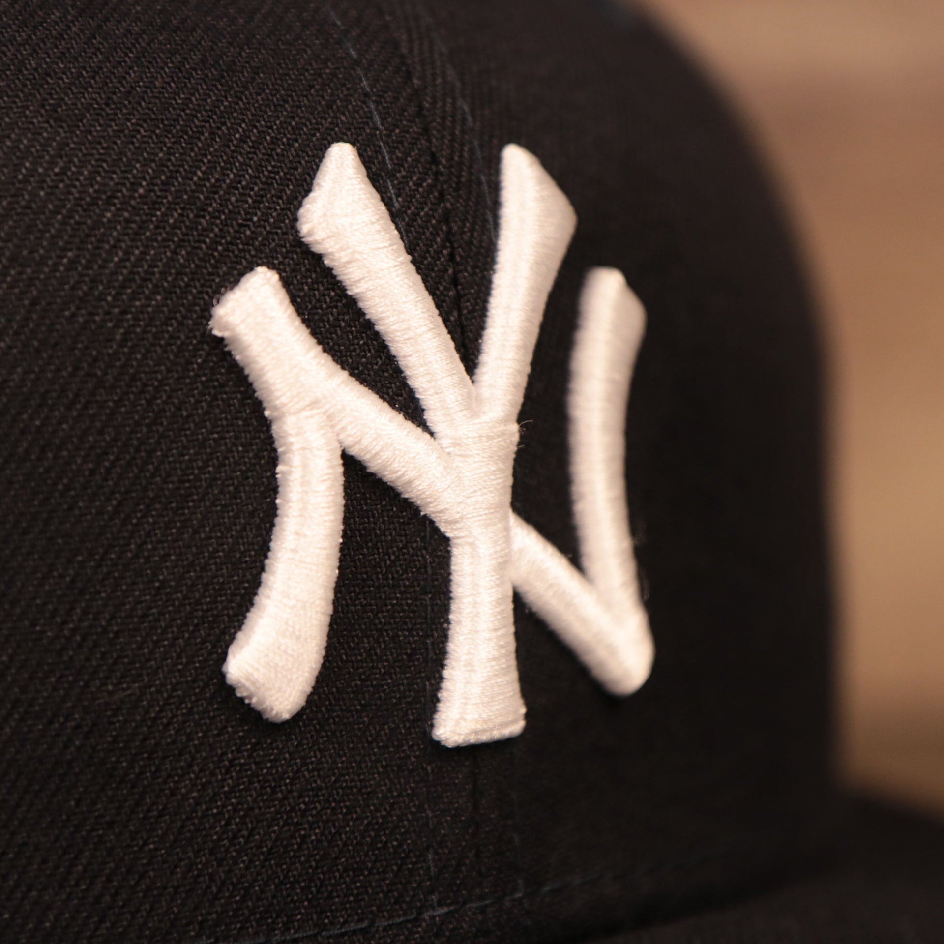 The New York Yankees logo patch on the front side of the navy New Era mesh snapback hat.