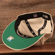 The green bottom brim of the cream Philadelphia Eagles retro logo patch 59fifty cap by New Era.
