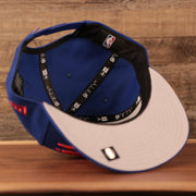 The gray bottom brim of the youth Philadelphia 76ers royal blue logo tear 9fifty snapback hat.