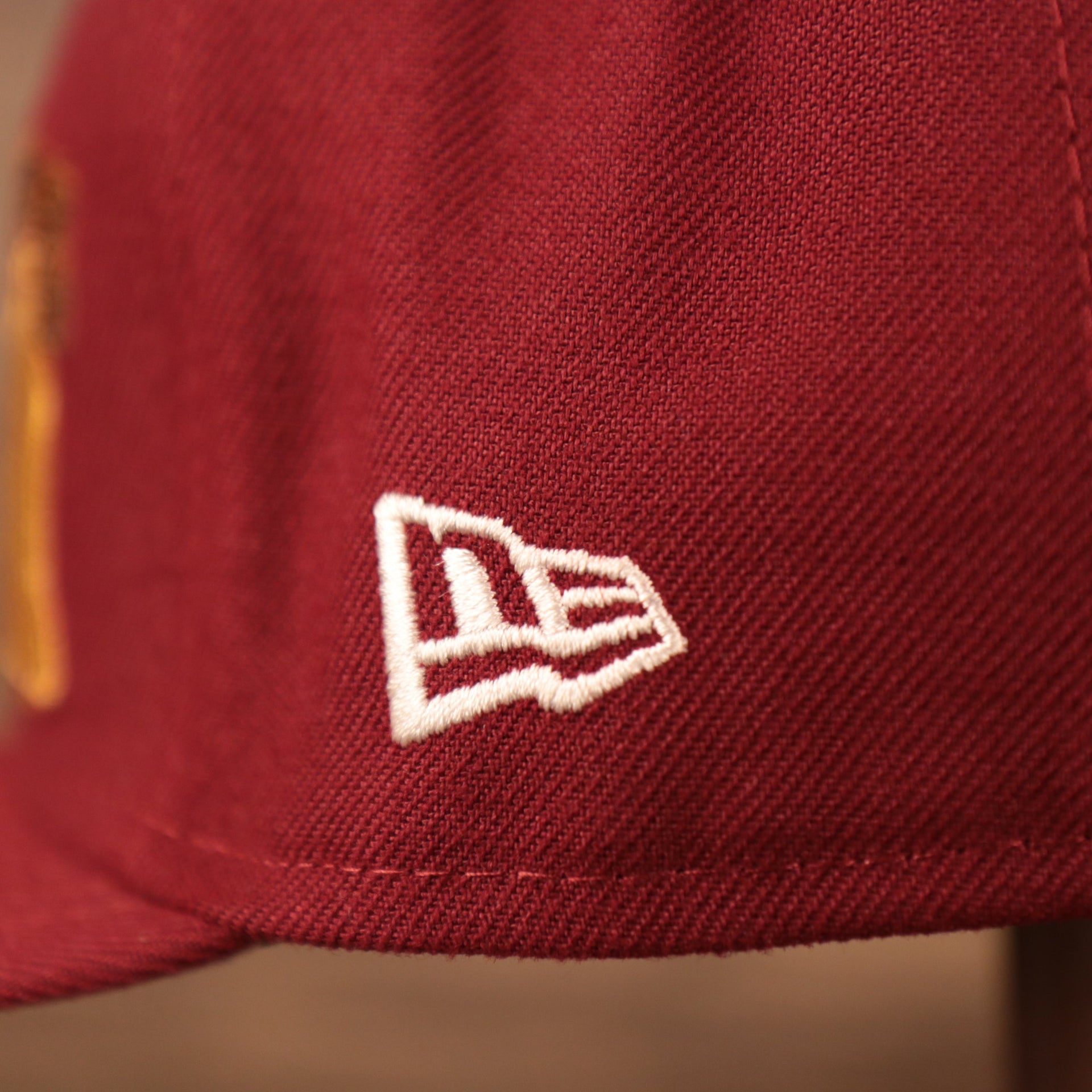 A close up shot of the white New Era logo embroidered on the left side of the maroon Philadelphia Phillies grey bottom brim retro 5950 side patch fitted hat.
