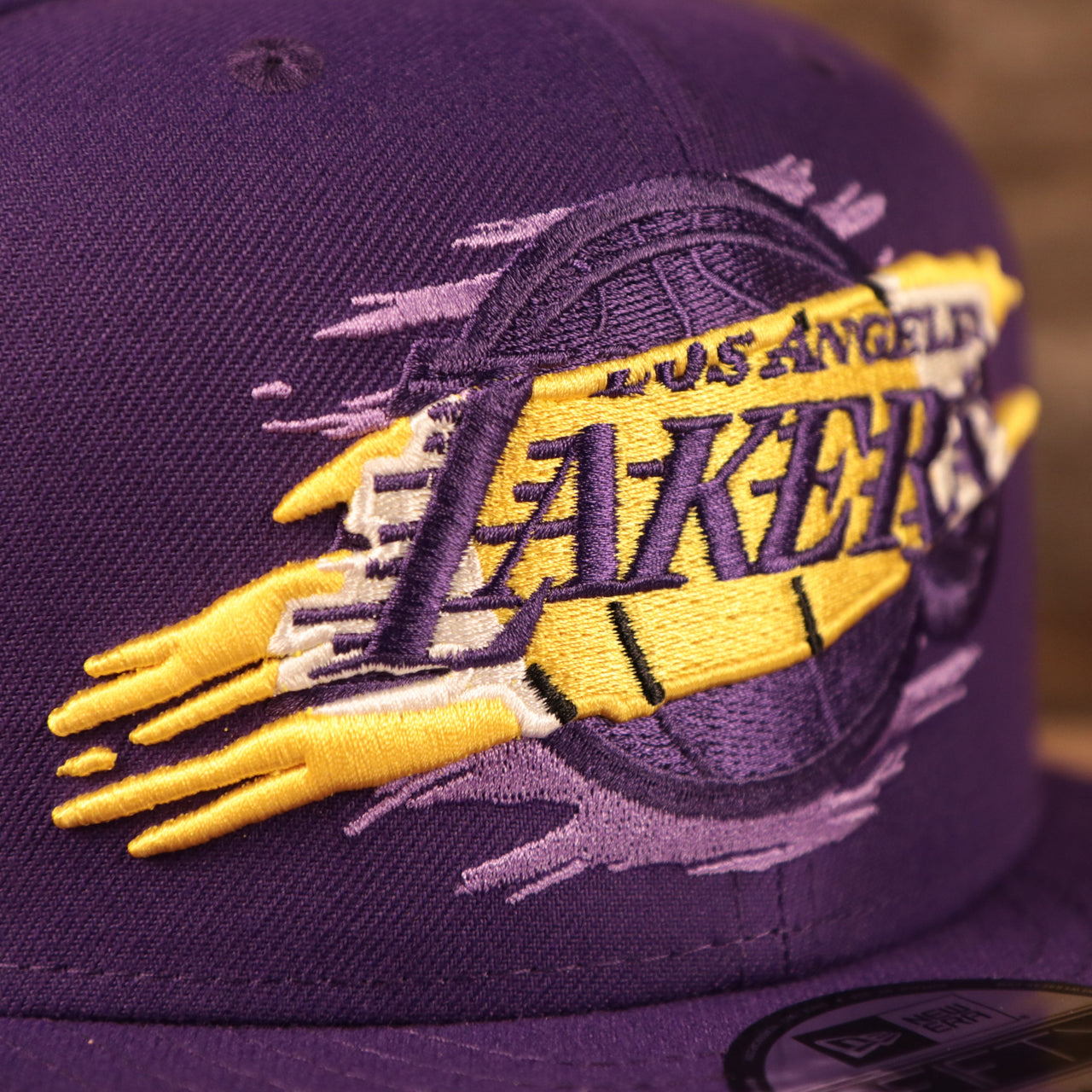 The Los Angeles Lakers logo tear patch on the front side of the purple 950 snapback hat.