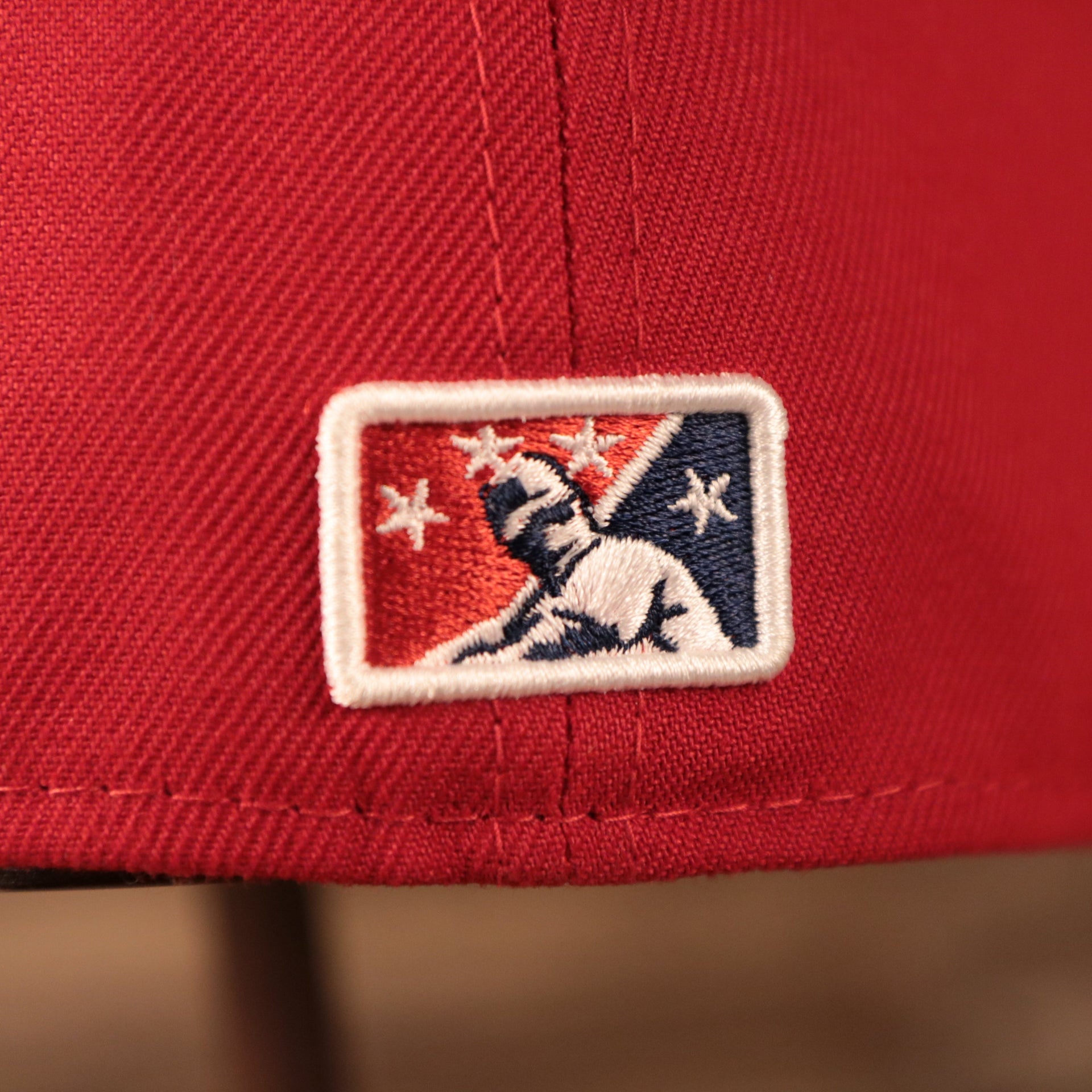 The backside of the red MiLB copa hat for the Lehigh Valley Iron Pigs has the Minor League Baseball logo.