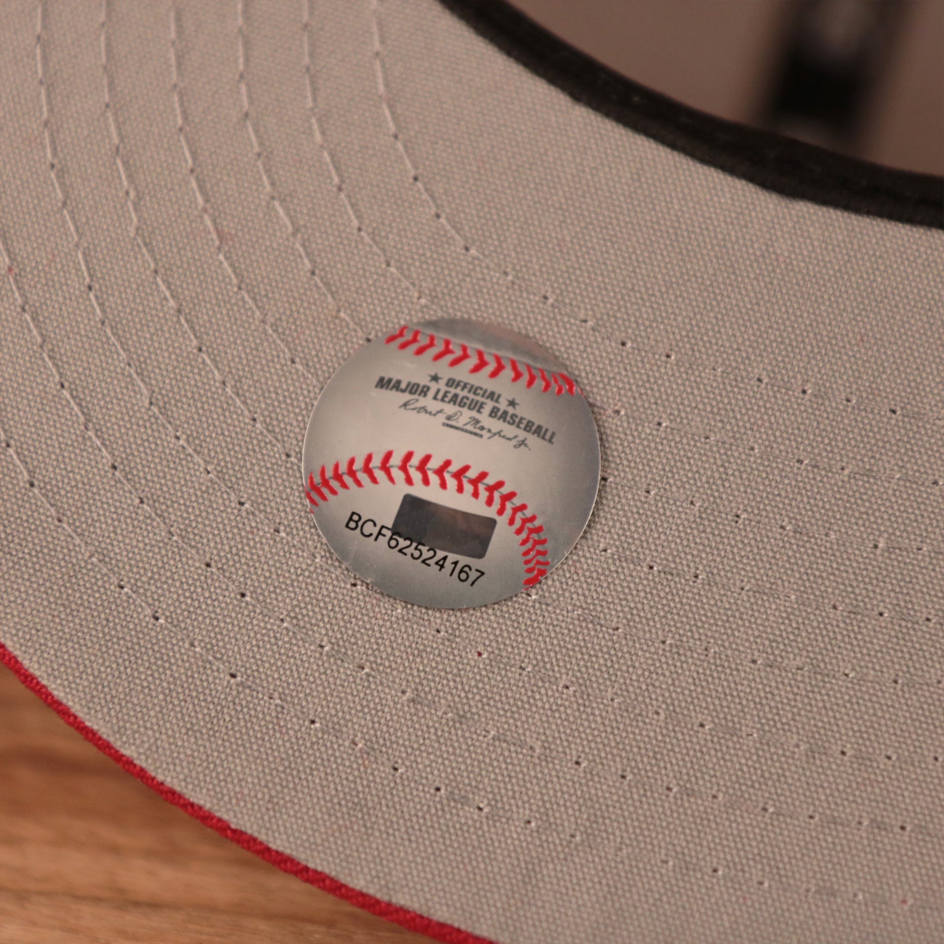 The official Major League Baseball logo sticker on the gray underbrim of the red all over patch fitted New Era cap.