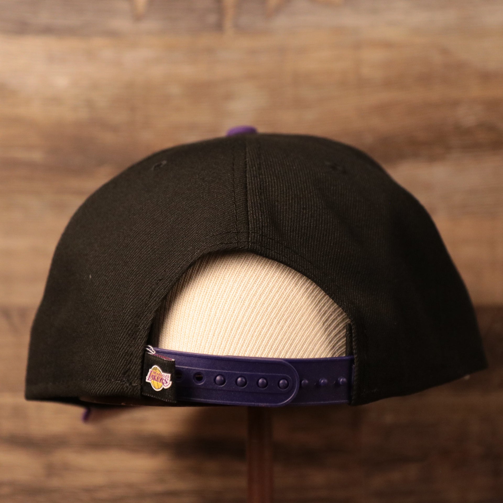 The adjustable strap of the Los Angeles Lakers black/pruple 950 fitted cap.