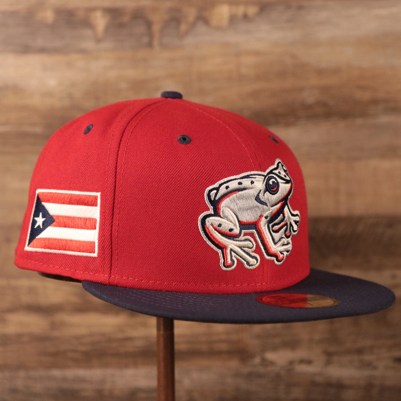 The coquis frog logo on the front of the red hispanic minor league fitted cap by New Era.