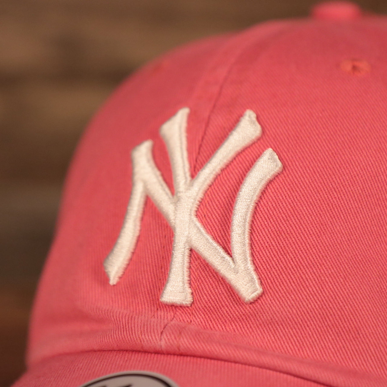 The white Yankees logo on the front of the pink cotton green bottom dad hat.